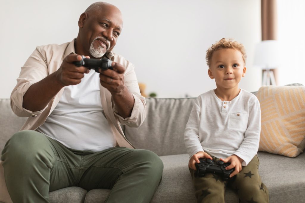 Black Grandfather And Grandson Playing Videogames Having Fun At Home